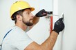 © Kostiantyn - Portrait of male worker professional electrician in uniform installing electrical outlet in apartment after renovation work