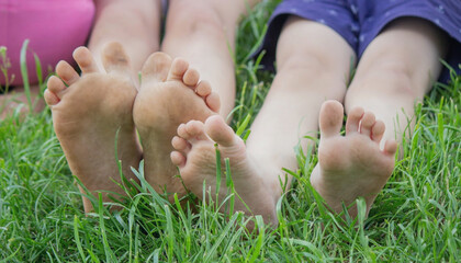 Wall Mural - Children's legs on green grass. Selective focus.