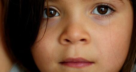 Wall Mural - Thoughtful little girl macro close-up face. Pensive child looking at camera