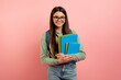 Portrait of smiling teenage girl student with backpack, workbooks, and eyeglasses