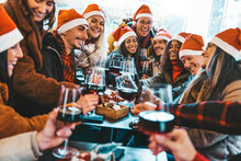 Happy people wearing santa claus hat having Christmas dinner party - Cheerful group of friends celebrating new year together - Winter holidays concept