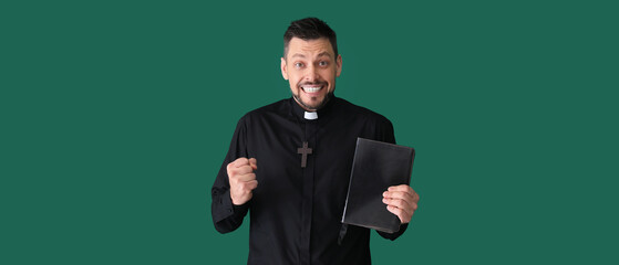 Happy priest with Bible on green background