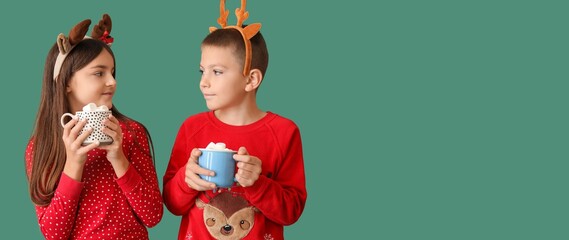 Wall Mural - Little children with reindeer antlers drinking hot chocolate on green background with space for text