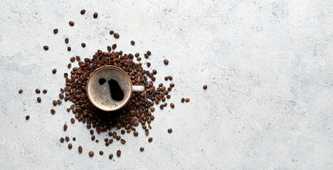 Cup of coffee and scattered beans on light blue grunge background