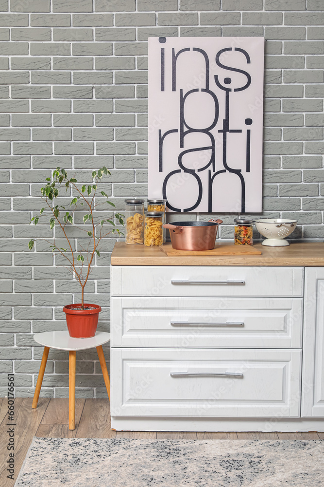 Kitchen counter with cooking pot, cutting board, jars and houseplant