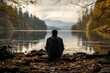 A contemplative image of a person staring out into the horizon at a tranquil lake, conveying a sense of solitude and inner reflectio