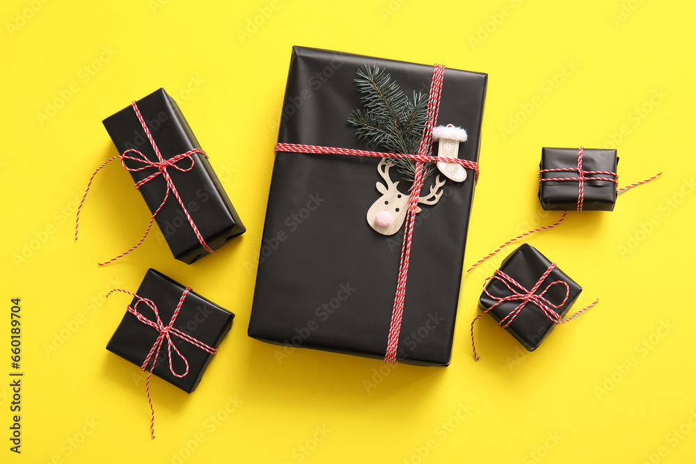 Black gift boxes with Christmas tree branch and beautiful decorations on yellow background