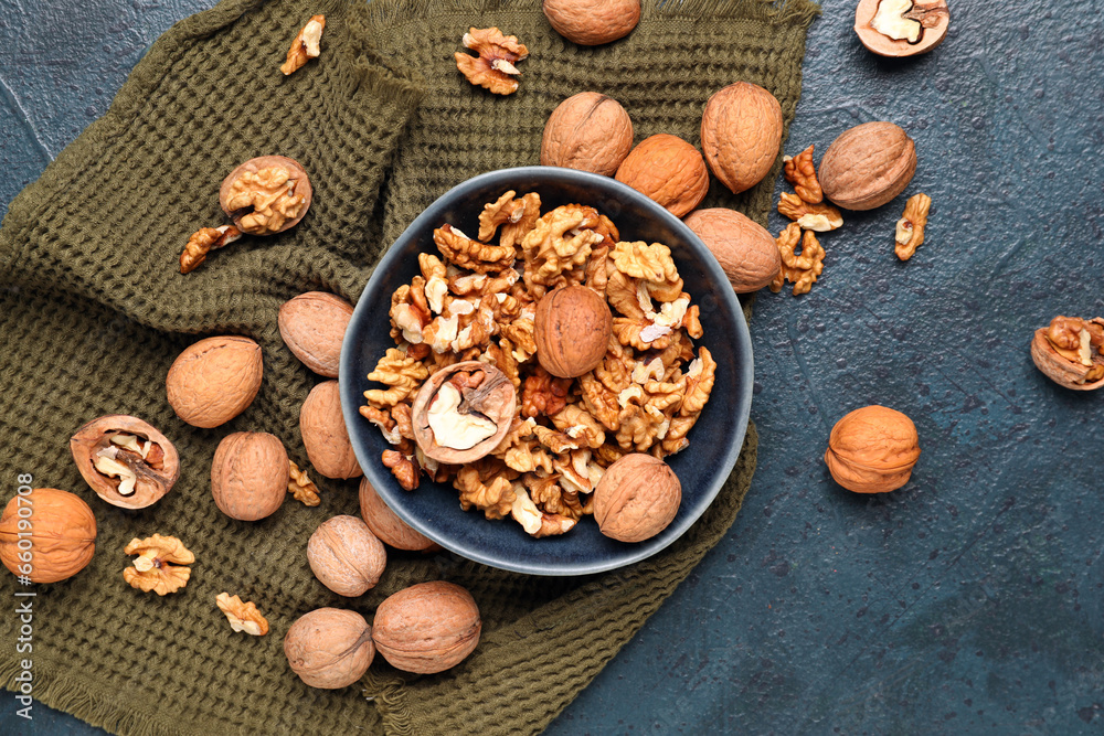 Bowl with tasty walnuts on black background