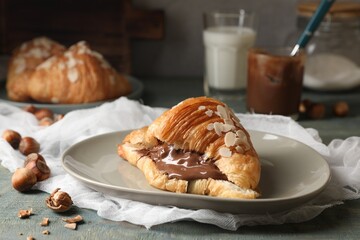 Wall Mural - Delicious croissant with chocolate and nuts on light blue wooden table