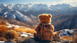 Teddybär mit Rucksack sitzt auf der Spitze eines Berges.