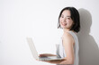 © kapinon - Young student-like woman studying typing using a computer, looking at the camera.