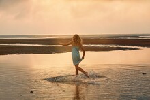 A Young Girl Plays In A Pool Of Water Left By The Ocean Tide As It Recedes 