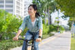 Beautiful happy Asian woman in casual clothes looks around while commuting on a morning bicycle. Lifestyle concept