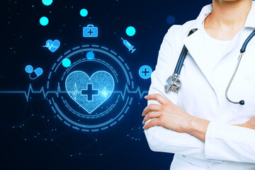 Wall Mural - Close up of folded female doctor arms with glowing bright medical heart interface on blurry blue background. Innovation and cardiology concept.
