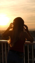 silhouette of a woman watching the sunset and listening to music on headphones