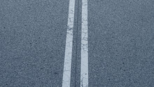 An Asphalt Road. Close-up Of A Traffic Road. White Line On A Road. Cracked Paint Line Of A Road.