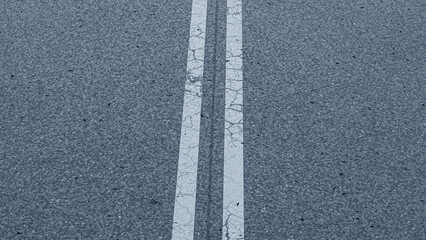 an asphalt road. close-up of a traffic road. white line on a road. cracked paint line of a road.