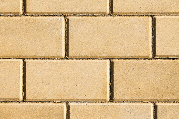 Wall Mural - Yellow brick pavement texture. Even blocks pattern. Brick flooring. Outdoor sunny texture. Walkway background. Brick pattern. Closeup construction.