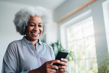 Portrait of a relaxed senior woman laughing while using her smartphone at home. Modern lifestyle of the elderly people. 