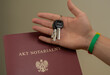 Klucz do nowego mieszkania trzymany na tle aktu notarialnego 