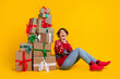 Full size photo of impressed girl dressed sweatshirt astonished staring at christmas gift boxes isolated on yellow color background