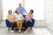 © artitwpd - The group of happy and healthy three Asian senior women sits together on a sofa with an Asian senior man standing in the back. Smiling and laughing together. Image with copy space