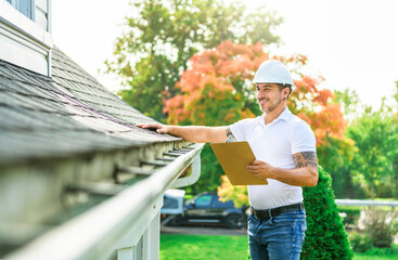 Wall Mural - Man with a white hard hat holding a clipboard, inspect house roof