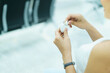© DG PhotoStock - Asian female backpacker tourist using true wireless headphones while sitting in the airport terminal. Woman picking a wireless earphones from charging case and put it into her ears.