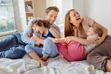 Happy young family playing and having fun on the bed at home