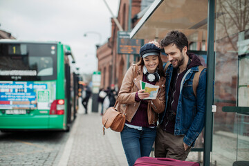 Young tourist couple looking at the map in the bus stop