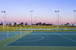 © Austockphoto - Dusk sky behind empty netball courts in sports park
