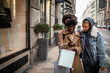 © Marko Geber - Young mixed lesbian couple shopping and walking in the city