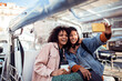 © Marko Geber - Two diverse female friends taking selfies on a sightseeing car while on vacation in the city