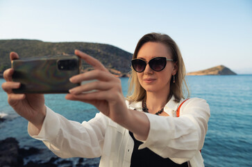 Wall Mural - Woman takes selfie on the seashore during vacation.