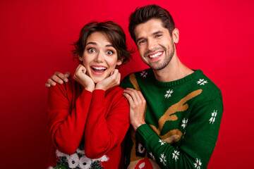 Poster - Photo of dreamy excited married couple wear ornament sweaters arms cheeks cuddling isolated red color background