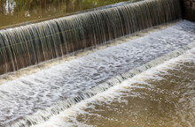 A Background View Of A Violent Flood Flowing Across A Concrete Dam And Spillway.
