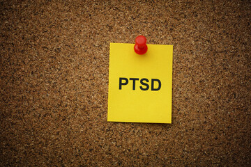 Wall Mural - A yellow paper note with the abbreviation PTSD (Posttraumatic stress disorder) on it pinned to a cork board