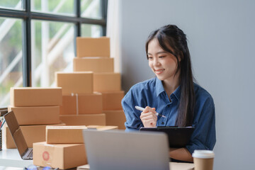 Wall Mural - E-commerce Entrepreneurship. Asian Female Online Seller Packing Orders for Internet Sales. Efficient Online Sales. Asian Female owner Packaging Products for Delivery.