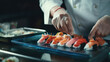 Japanese cuisine, the process of making rolls and sushi. A close-up of the hands of a sous-chef preparing Japanese traditional dishes in restaurant kitchen. 