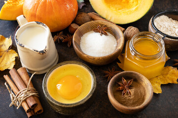 Wall Mural - Baking background for Thanksgiving or autumn holidays. Homemade fall baking background with ingredients pumpkins, sugar, flour, nuts, eggs and spices on a dark stone table.