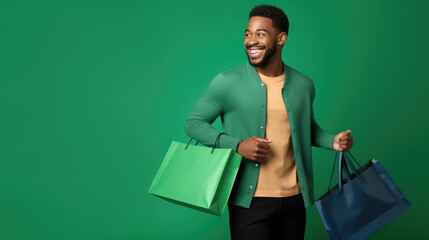 Wall Mural - Happy smiling man holding shopping bags on green background