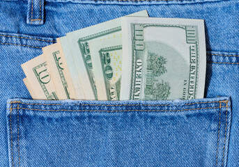 Paper American dollar bills protrude from the back pocket of blue jeans