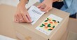 © CineLens/peopleimages.com - Online order, delivery label and woman hand with small business sticker for cardboard box. Stock, startup process and sales of ecommerce and boutique at home of a entrepreneur with courier package