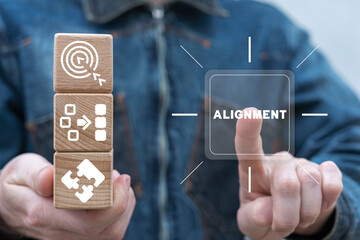 Man holding wooden cubes with icons and presses virtual button with word: ALIGNMENT. Business alignment strategy concept. Ideas for creativity. Ordering or alignment.