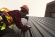 © RooM The Agency - Construction worker installing metal sheets on a roof, Thailand