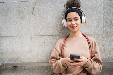 Wall Mural - One young sporty woman with headphones use mobile phone app for music