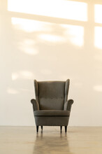 Classic English Armchair On The Background Of An Empty Wall. Sunset Light On The Wall. Vertical Photo