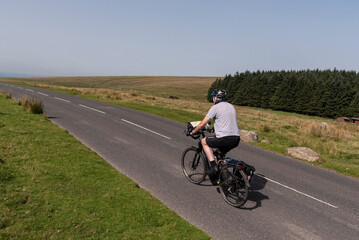 Dartmoor, Devon, Englaand, UK. 04.09.2023.  Man cycling on  an empty road  in Dartmoor national park in Devon, UK