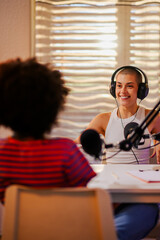 Wall Mural - The cheerful interracial podcasters are sitting in a small home broadcasting studio