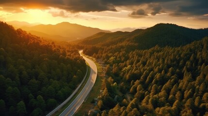 Wall Mural - Top view of mountain road in forest at sunset